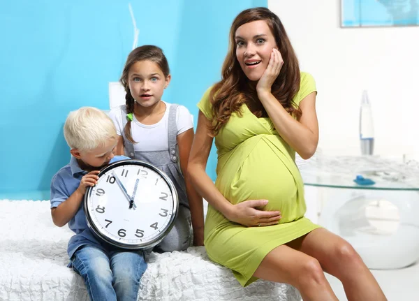 Mãe grávida e crianças com um relógio — Fotografia de Stock