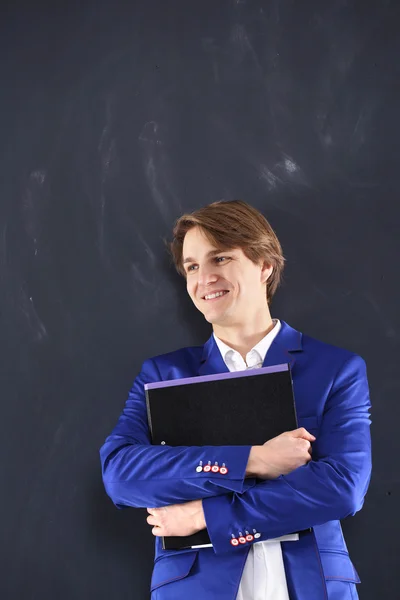 Молодой студент в синей куртке на фоне стола — стоковое фото