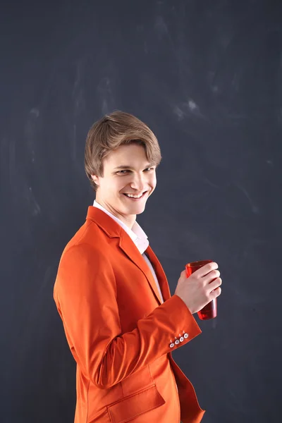 Vrolijke jongen in oranje jas met een kopje koffie — Stockfoto