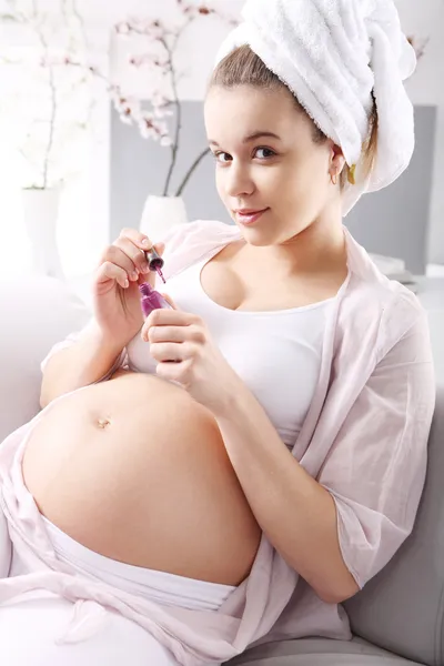 Mulher grávida bonita pintando unhas — Fotografia de Stock