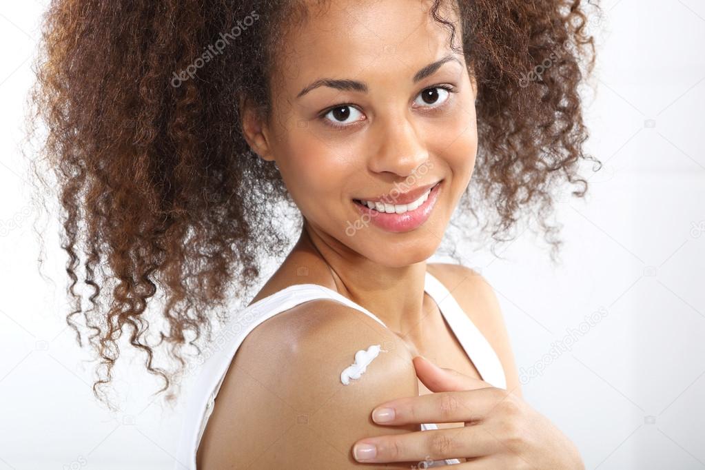 Dark skinned teen smiles rubbing cream