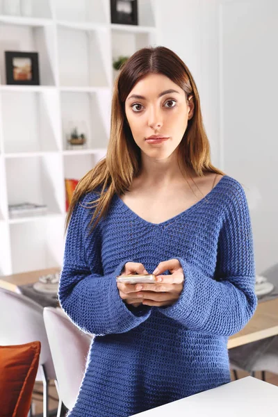 拿着电话的女人一个拿着手机的女人站在客厅里 — 图库照片