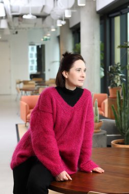 Work in a corporation. Woman in the office. Young woman in a pink sweater in the city center