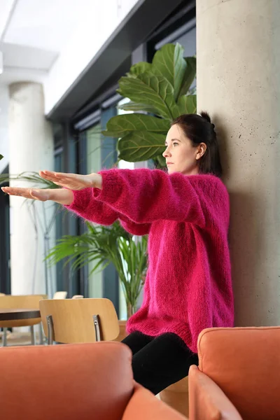 Exercises in the office, an active break at work. A young woman in a pink sweater in a the city center