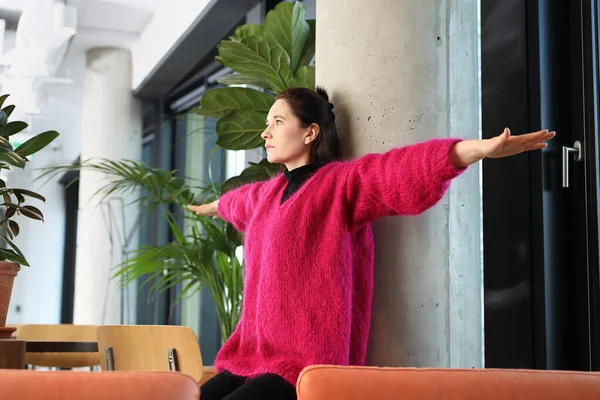 Exercises in the office, an active break at work. A young woman in a pink sweater in a the city center
