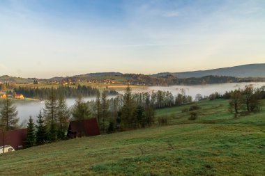 Gün doğumunda dağlarda sis var.