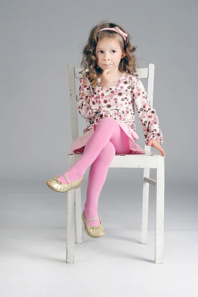 Portrait of beautiful little thoughtful girl on the white chair. — Stock Photo, Image