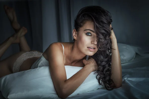 Sexy brünette Frau posiert im Bett — Stockfoto