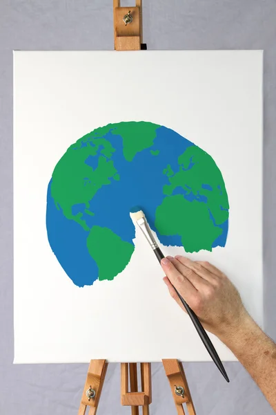 Artist painting a picture of the earth on a canvas — Stock Photo, Image