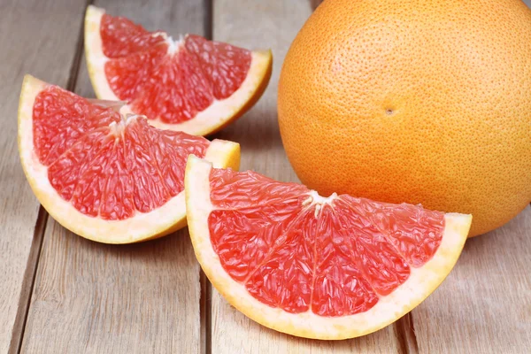 Pomelo rojo en rodajas sobre fondo de madera —  Fotos de Stock