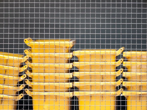 Yellow trash bin behind wire fence — Stock Photo, Image