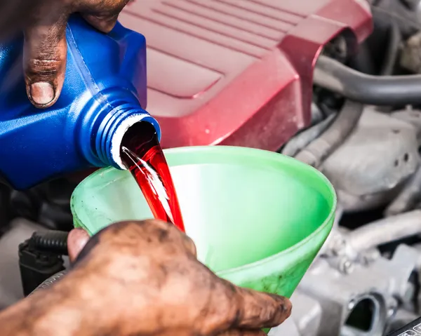 Hand gießt Übertragungsflüssigkeit durch Trichter — Stockfoto