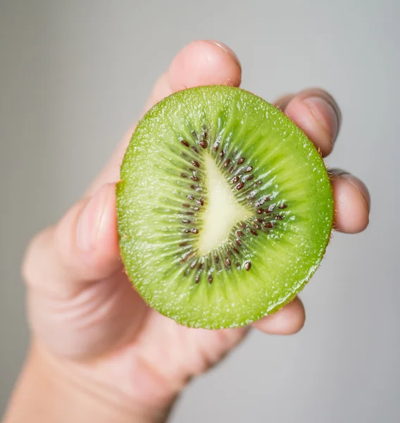 Mână cu jumătate de fruct kiwi — Fotografie, imagine de stoc