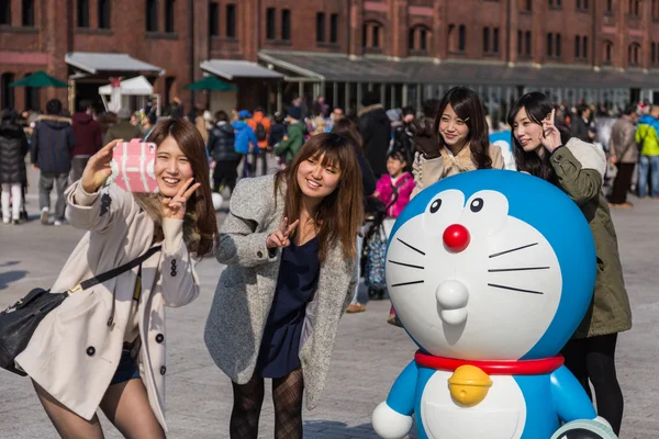Girls take photo with Doraemon figure — Stock Photo, Image