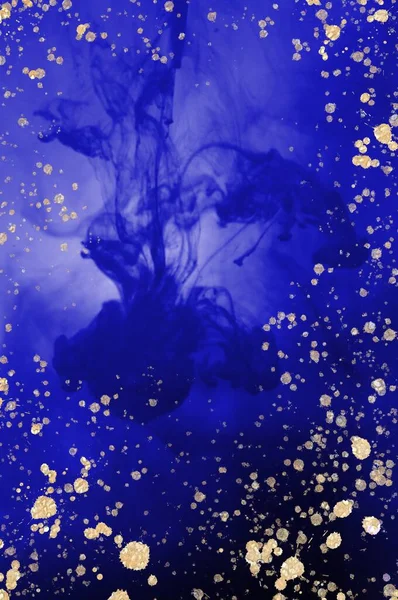 A big drop of blue ink in water. Alcohol ink fluid abstract texture fluid art with gold glitter and liquid with shades.