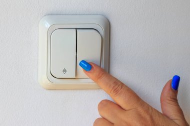 Woman's hand, switching off  the electricity panel for energy economy