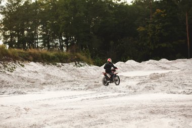 Motosikletli motorcuların kum ocağında gezintilerinin arka görüntüsü. Ekstrem eğlence kavramı. Duvar kağıdı. Uzayı metin için kopyala. Antrenman sporcuları motokros
