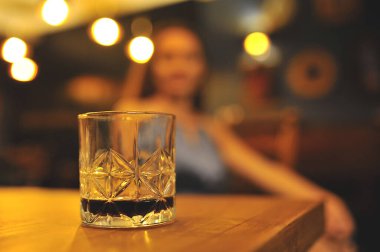 Woman sitting near table with whiskey in glass. Party Time. Celebration