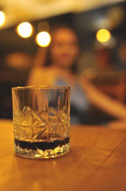  Bulanık kadın arka planında bir bardak viski. Parti zamanı. Sakin ol. Kutlama