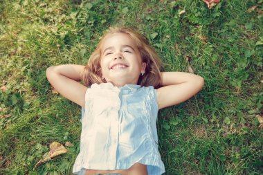 Küçük kız çimenlerde yatıyor.