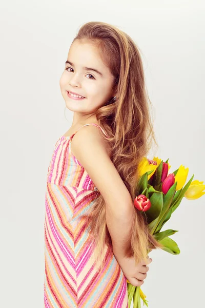 Mooi meisje met eerlijke haren in een roze jurk houdt bloemen — Stockfoto