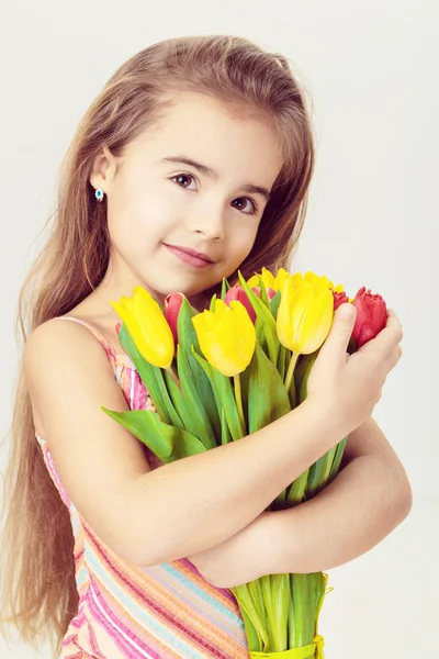 Schöne kleine Mädchen mit blonden Haaren in einem rosa Kleid hält Blumen — Stockfoto
