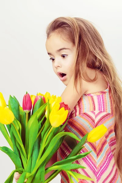 Удивлённая маленькая девочка с букетом тюльпанов — стоковое фото