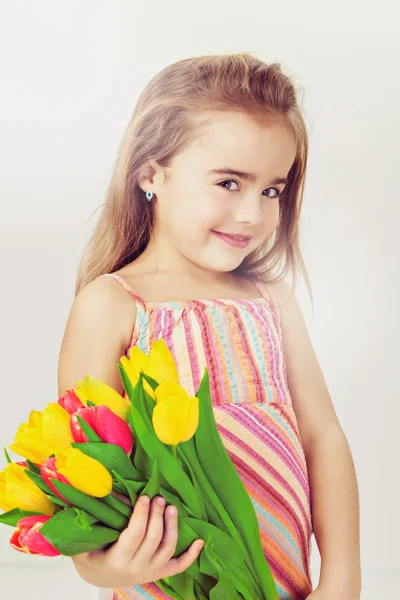 Hermoso niño con el pelo claro en un vestido rosa sostiene flores —  Fotos de Stock