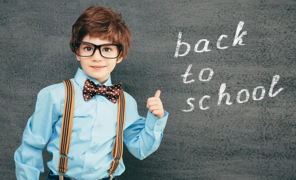 Cheerful little pupil against chalkboard — Stock Photo, Image
