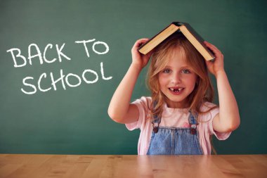 Okul çocuğu (kız) sınıfta. Yeşil karatahtaya karşı komik çocuk. Fikir ve yaratıcılık kavramı. Arka planda kopyalanma alanı. Okul konseptine dönelim.. 