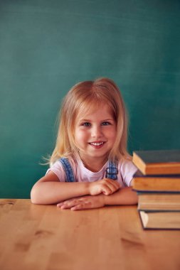 Okul çocuğu (kız) sınıfta. Yeşil karatahtaya karşı komik çocuk. Fikir ve yaratıcılık kavramı. Arka planda kopyalanma alanı. Okul konseptine dönelim.. 