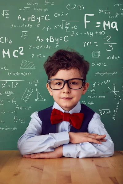 School child (boy) in classroom. Funny kid against green chalkboard. Idea and creativity concept. Copyspace on background. Back to school concept.