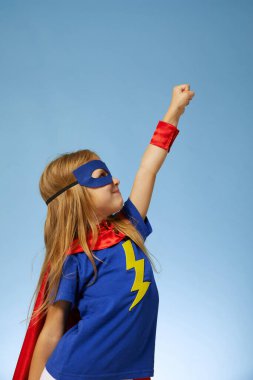 Kırmızı yağmurluk giyen komik, küçük süper kahraman çocuk. Mavi arka plana karşı komik çocuk. Fikir ve yaratıcılık kavramı.