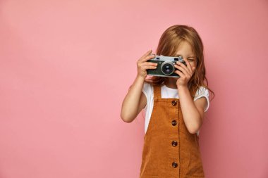 Güzel gülümseyen çocuk (çocuk, kız) elinde bir kamera tutuyor. Fotoğraf ve reklam kavramını öğren
