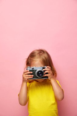 Güzel gülümseyen çocuk (çocuk, kız) elinde bir kamera tutuyor. Fotoğraf ve reklam kavramını öğren