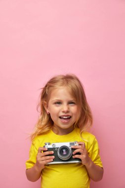 Güzel gülümseyen çocuk (çocuk, kız) elinde bir kamera tutuyor. Fotoğraf ve reklam kavramını öğren