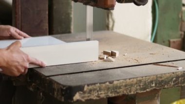 Marangoz ahşap işçisi atölyede mobilya yapmak için endüstriyel elektrikli odun kesme makinesiyle odun kesiyor.