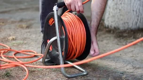 Ein Mann Wickelt Das Kabel Mit Elektrischer Kabeltrommel — Stockvideo