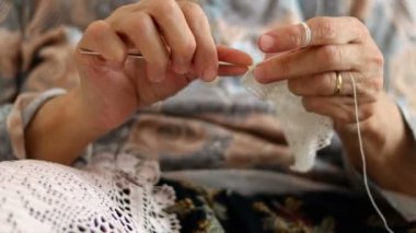 Handcrafted traditional knitting. Old woman makes canvas pattern stitches with sewing needle. Cover with thread
