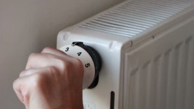 Kadın evdeki ısıtma kaloriferinin vanasını kapatıyor. Avrupa 'da ve dünyada enerji, yakıt ve LNG gaz krizi. Yakıt fiyatlarındaki artış