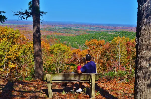 A couple sitting on a bench looking at fall color — Stock Photo, Image