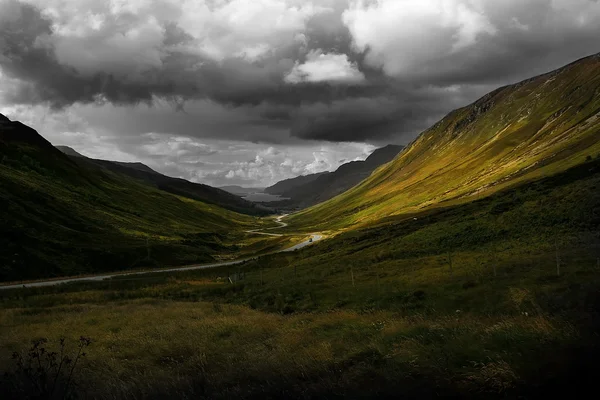 Road across scotland valley with clouds — Stock Photo, Image