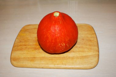 Kesme tahtasındaki küçük turuncu balkabağı. Sağlıklı yiyecekler. Cadılar Bayramı Dekorasyonları - Azizler arifesi.