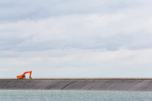 Backhoe on dam crest — Stock Photo, Image