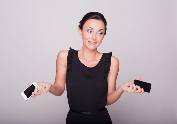 The beautiful girl holds two phones — Stock Photo, Image