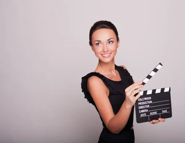 En attraktiv ung kvinna håller en öppen film skiffer — Stockfoto