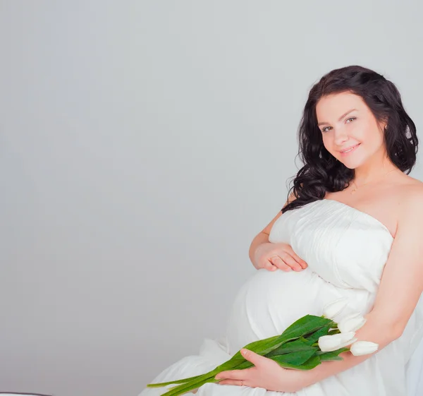 Těhotná žena s bílými tulipány — Stock fotografie