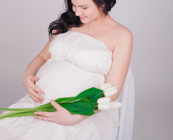 Zwangere vrouw met witte tulpen — Stockfoto