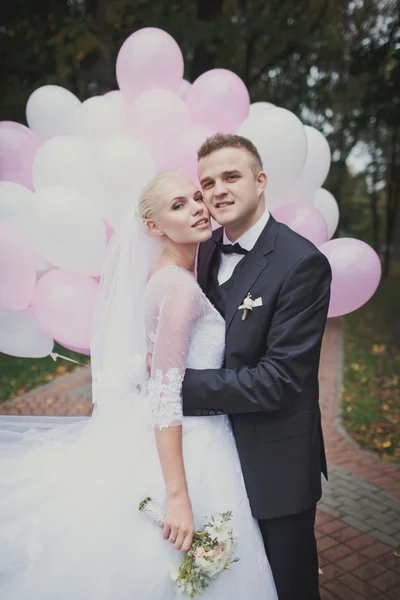 Novio y novia posando sobre un fondo de globos — Foto de Stock