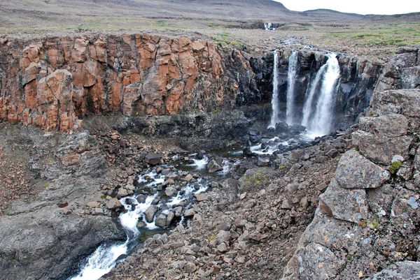 Un paisaje rocoso con una cascada . — Foto de Stock